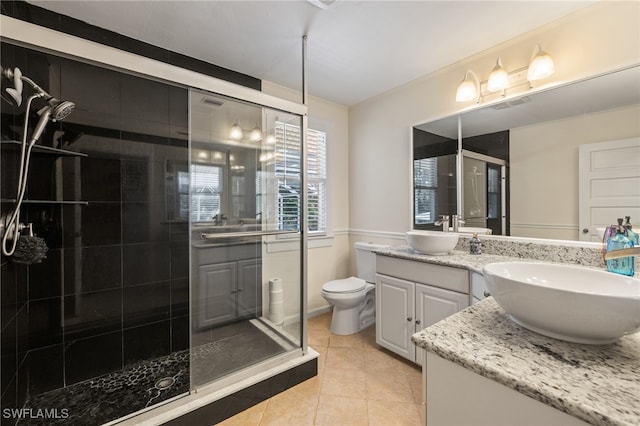 bathroom with vanity, toilet, tile patterned floors, and a shower with shower door