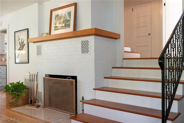 stairs featuring a brick fireplace