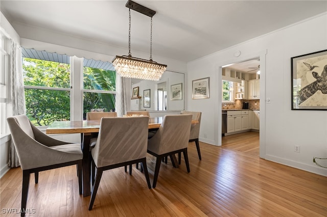 dining space with light hardwood / wood-style flooring and ceiling fan with notable chandelier