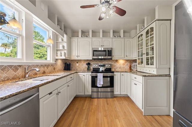 kitchen with white cabinetry, light stone countertops, appliances with stainless steel finishes, and light wood-type flooring