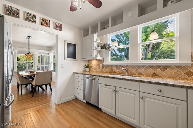 kitchen featuring tasteful backsplash, appliances with stainless steel finishes, sink, white cabinetry, and light hardwood / wood-style flooring