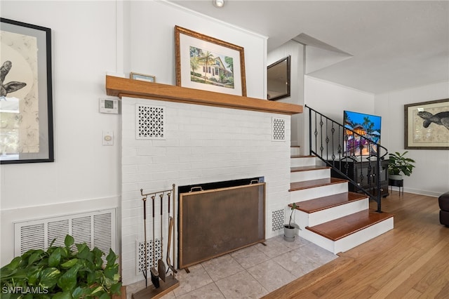 staircase with a fireplace and wood-type flooring