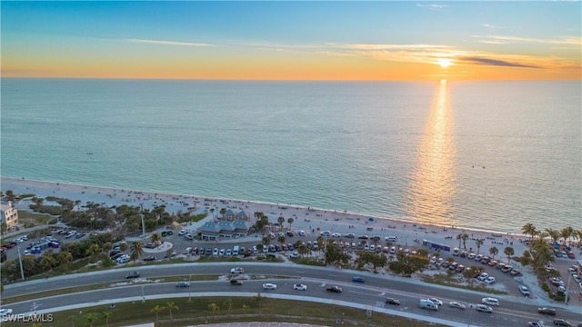 aerial view at dusk with a water view and a beach view