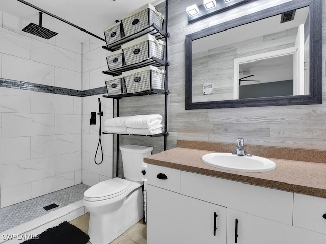 bathroom featuring vanity, toilet, a tile shower, and tile patterned flooring