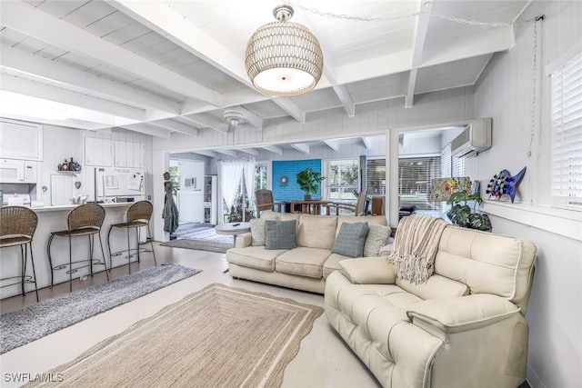 living room with beamed ceiling, an AC wall unit, and a wealth of natural light