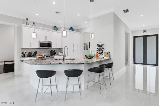 kitchen with white cabinets, stainless steel appliances, stone countertops, kitchen peninsula, and pendant lighting