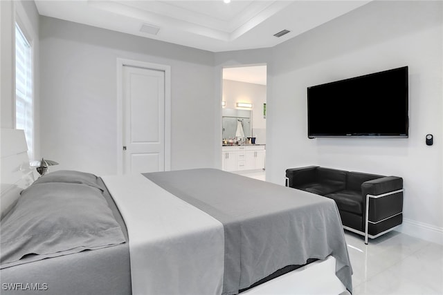 bedroom featuring a raised ceiling and ensuite bath