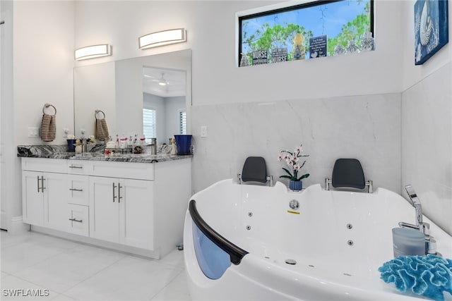 bathroom with a tub to relax in, vanity, tile walls, and tile patterned floors