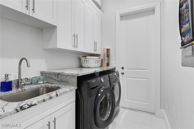 clothes washing area featuring cabinets, washer and clothes dryer, and sink