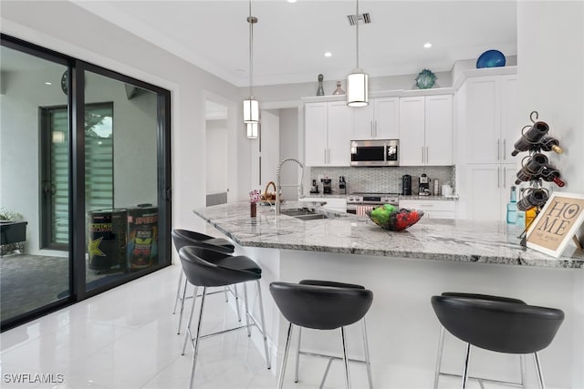 kitchen with white cabinetry, sink, light stone countertops, hanging light fixtures, and appliances with stainless steel finishes