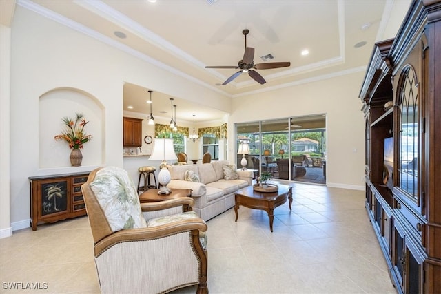 tiled living room featuring a raised ceiling, ceiling fan, and ornamental molding