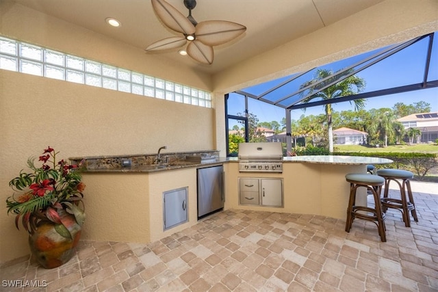 view of patio featuring an outdoor kitchen, ceiling fan, a lanai, sink, and a grill