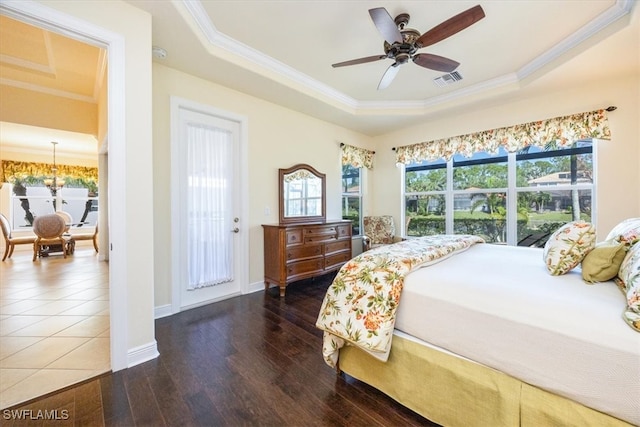 bedroom with dark wood-type flooring, ceiling fan, a tray ceiling, and multiple windows