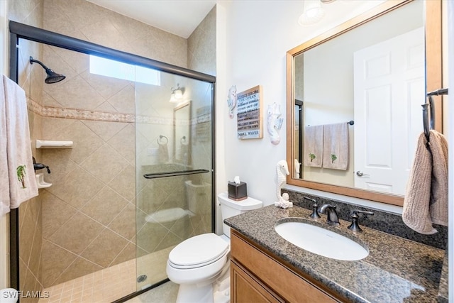 bathroom with toilet, vanity, and a shower with shower door