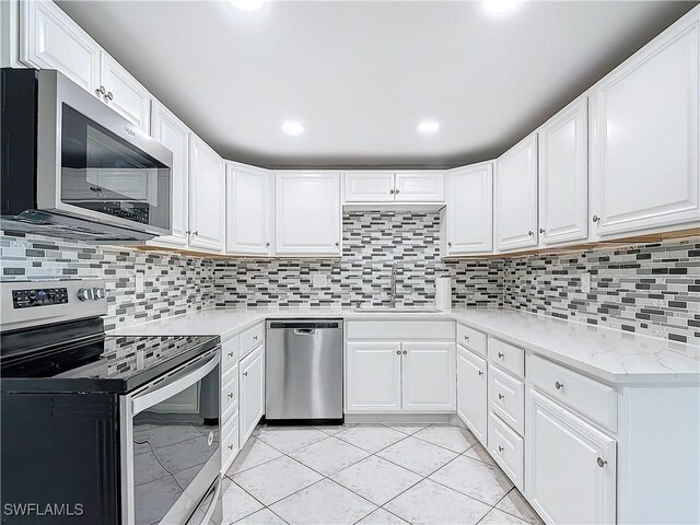 kitchen with white cabinetry, sink, light tile patterned floors, and stainless steel appliances