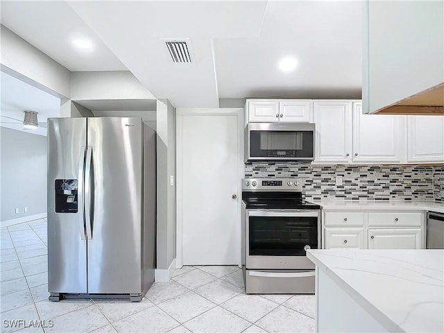 kitchen with light stone counters, tasteful backsplash, white cabinets, and appliances with stainless steel finishes