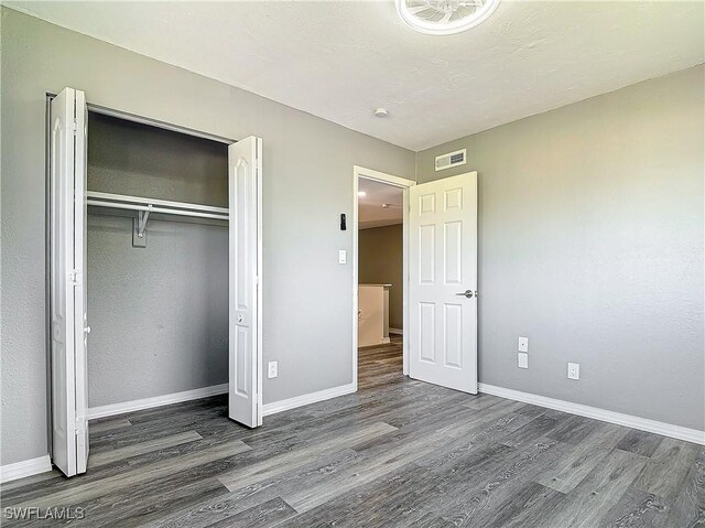 unfurnished bedroom featuring dark hardwood / wood-style flooring, a closet, and a textured ceiling