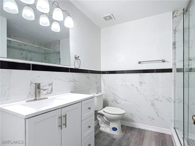 bathroom featuring hardwood / wood-style floors, tile walls, vanity, an enclosed shower, and toilet