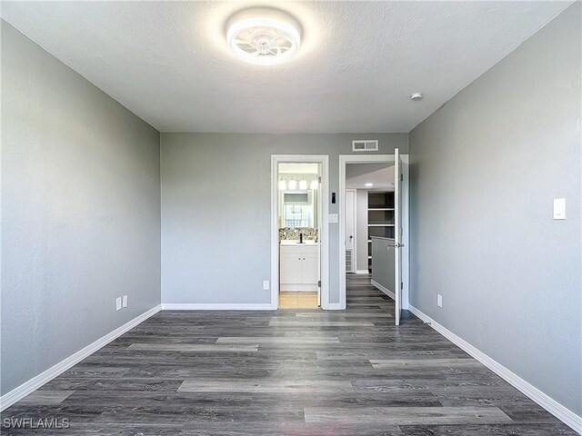 spare room featuring dark wood-type flooring, sink, and a textured ceiling