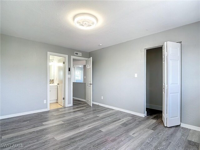 unfurnished bedroom featuring hardwood / wood-style flooring, a textured ceiling, and ensuite bathroom