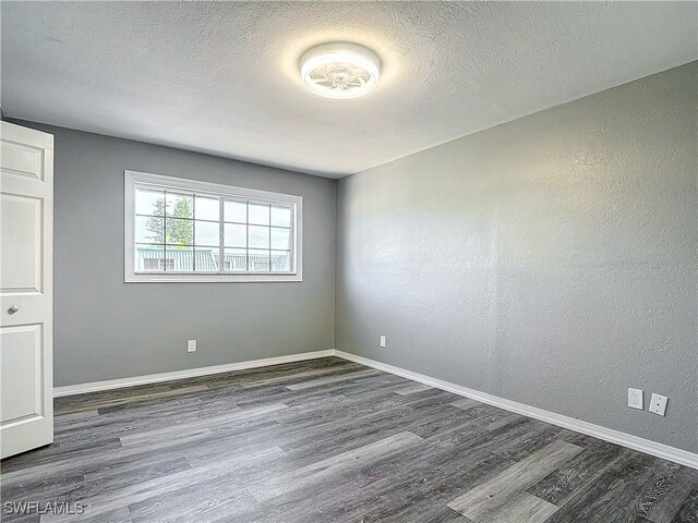 unfurnished room featuring dark hardwood / wood-style flooring and a textured ceiling