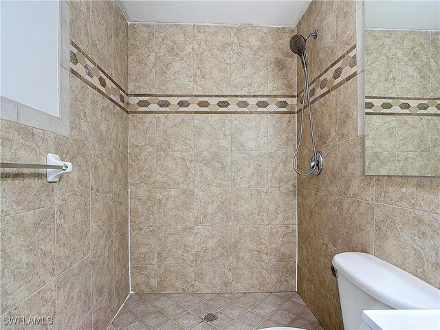 bathroom with a tile shower and toilet