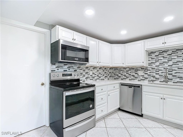 kitchen with sink, decorative backsplash, light tile patterned floors, appliances with stainless steel finishes, and white cabinetry