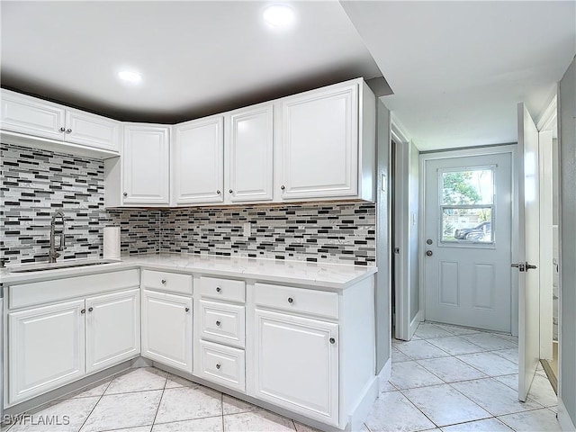 kitchen featuring tasteful backsplash, white cabinetry, sink, and light tile patterned floors