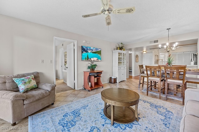 tiled living room featuring a textured ceiling and ceiling fan with notable chandelier