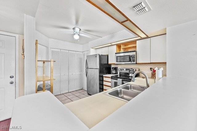 kitchen with light hardwood / wood-style floors, stainless steel appliances, sink, white cabinetry, and ceiling fan