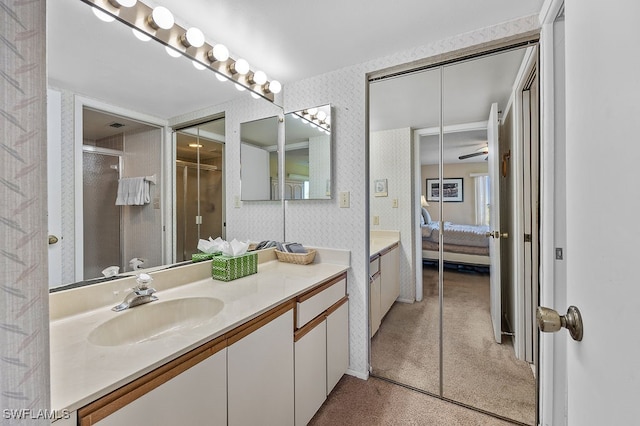 bathroom with vanity, a shower with shower door, and ceiling fan