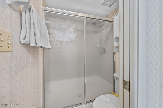 bathroom with a shower with door and toilet