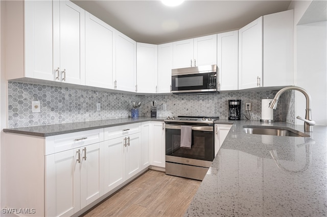 kitchen featuring light wood-type flooring, light stone counters, sink, white cabinets, and appliances with stainless steel finishes