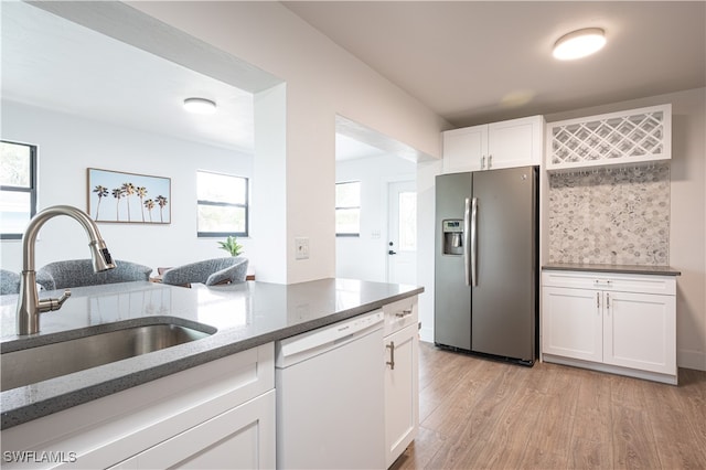 kitchen with white dishwasher, stainless steel fridge, sink, light hardwood / wood-style flooring, and white cabinetry