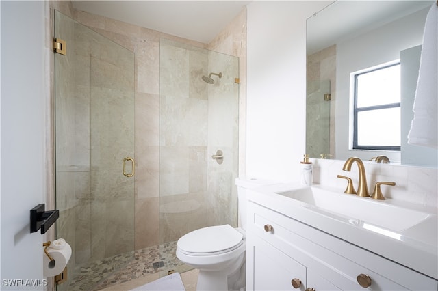 bathroom featuring vanity, a shower with shower door, and toilet