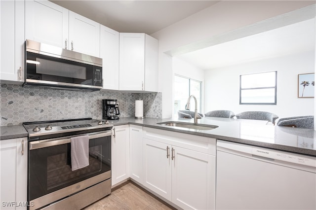 kitchen with light wood-type flooring, sink, stainless steel appliances, and white cabinets