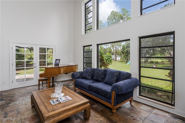 living room featuring a wealth of natural light, a high ceiling, and french doors