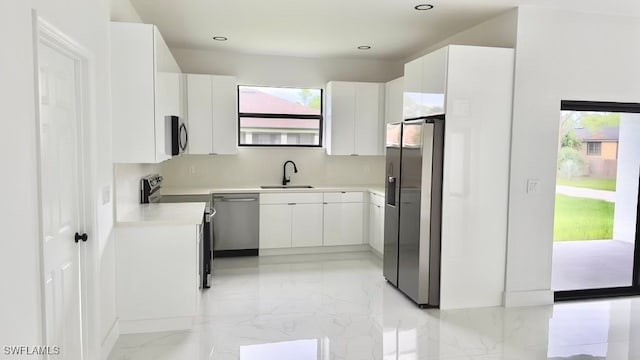 kitchen featuring a healthy amount of sunlight, stainless steel appliances, sink, and white cabinets