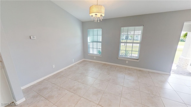 tiled empty room featuring vaulted ceiling and an inviting chandelier