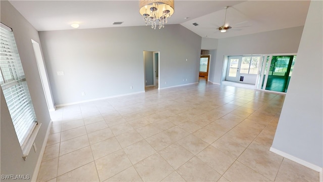 tiled empty room with high vaulted ceiling and ceiling fan with notable chandelier