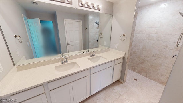 bathroom with tiled shower, vanity, and tile patterned floors