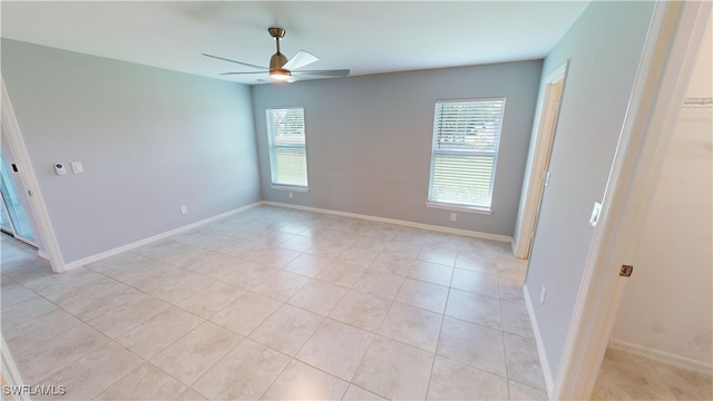 empty room with a wealth of natural light, light tile patterned flooring, and ceiling fan