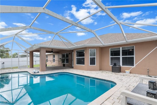 view of swimming pool with glass enclosure, ceiling fan, and a patio