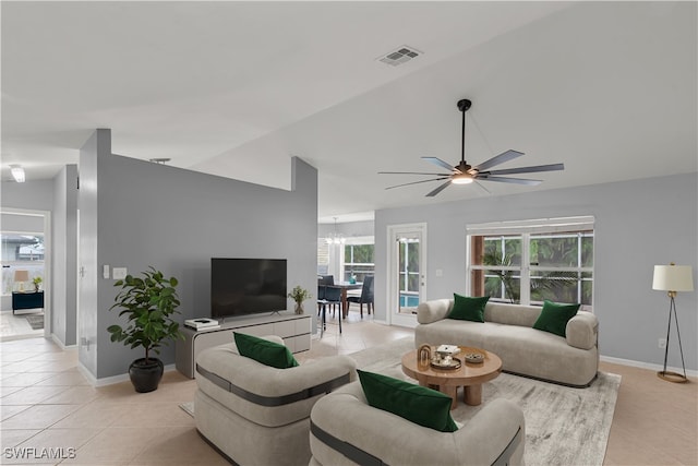 tiled living room featuring ceiling fan with notable chandelier and vaulted ceiling