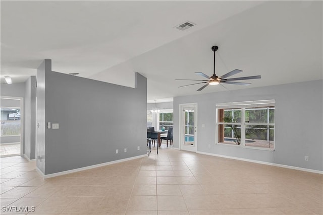 tiled empty room featuring lofted ceiling and ceiling fan with notable chandelier