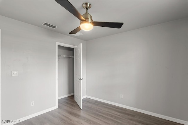 unfurnished bedroom featuring hardwood / wood-style floors, a closet, and ceiling fan