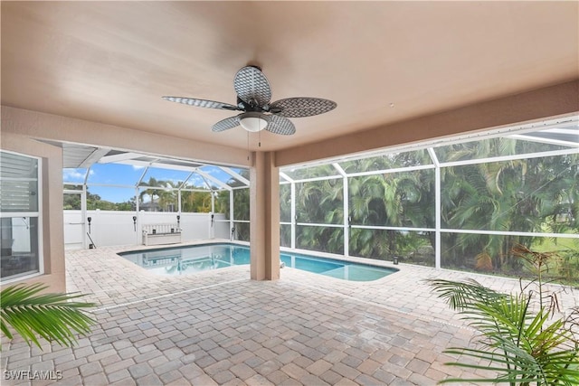 view of swimming pool with a patio area, ceiling fan, and glass enclosure