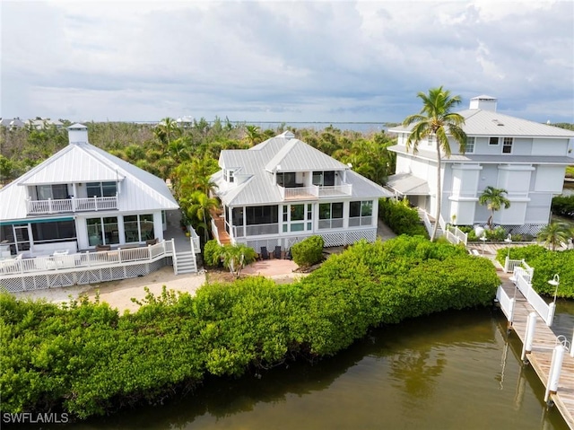 back of house with a balcony, a water view, and a chimney