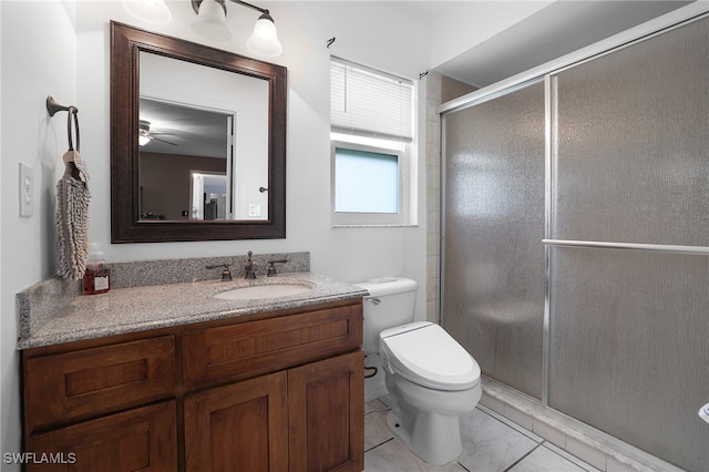 bathroom with vanity, toilet, ceiling fan, and a shower with door