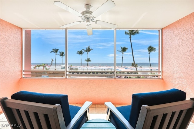 living area featuring a water view, a view of the beach, and ceiling fan